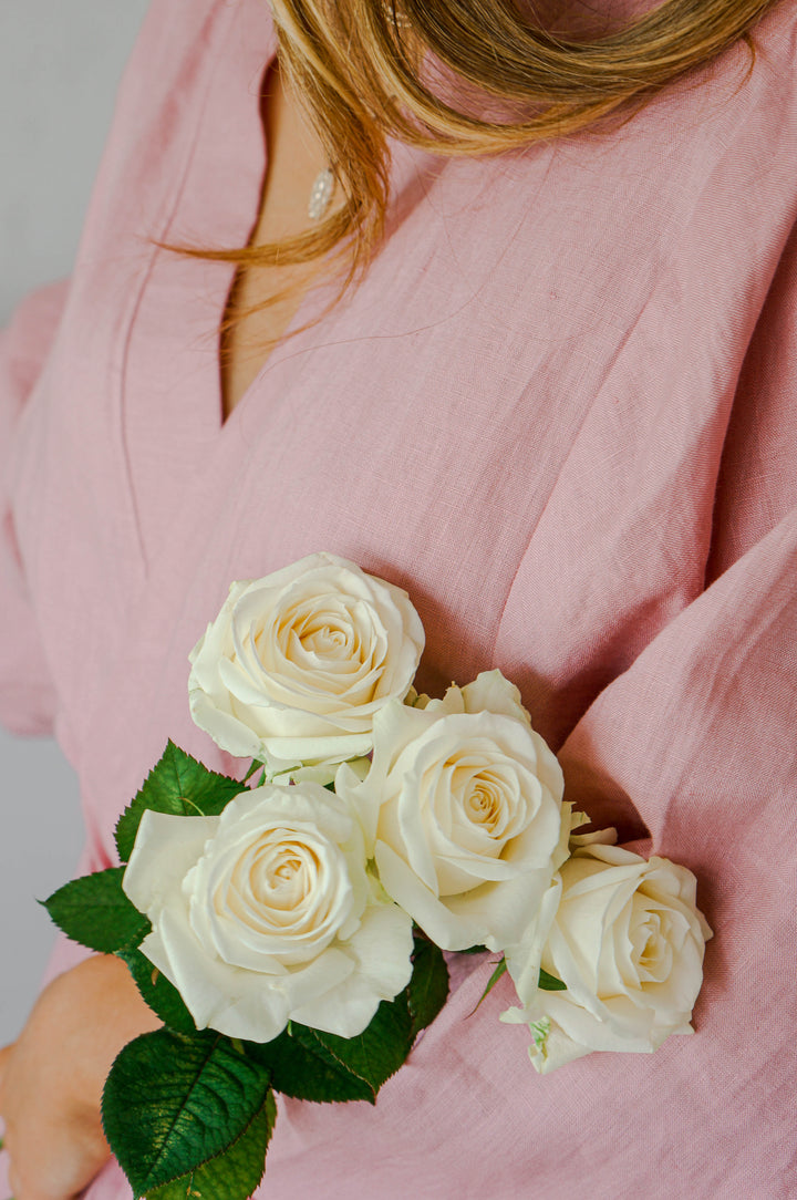 Bridesmaid wearing Harper pink linen robe holding flowers