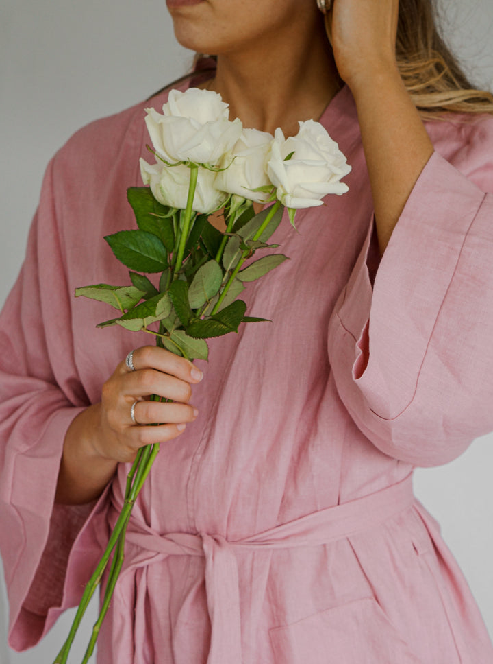 Bridesmaid wearing Harper pink linen robe holding flowers