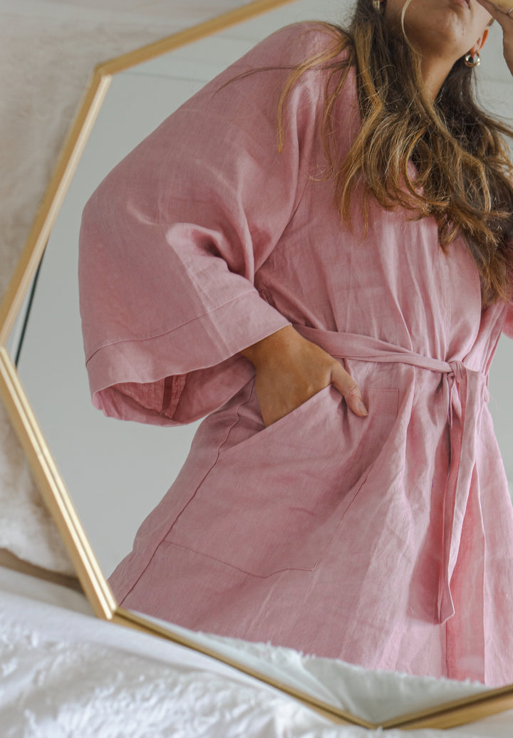 Bridesmaid wearing Harper pink linen robe looking in mirror