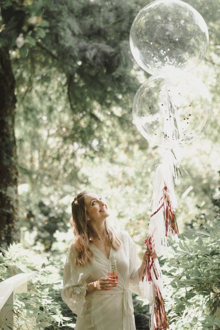Bride wearing Lily white satin lace bridal robe holding balloon